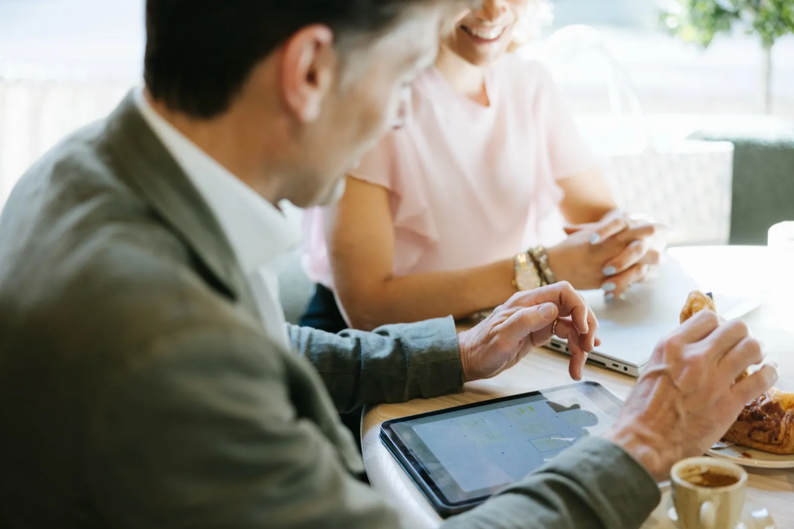 A meeting at a café table with a tablet and coffee.