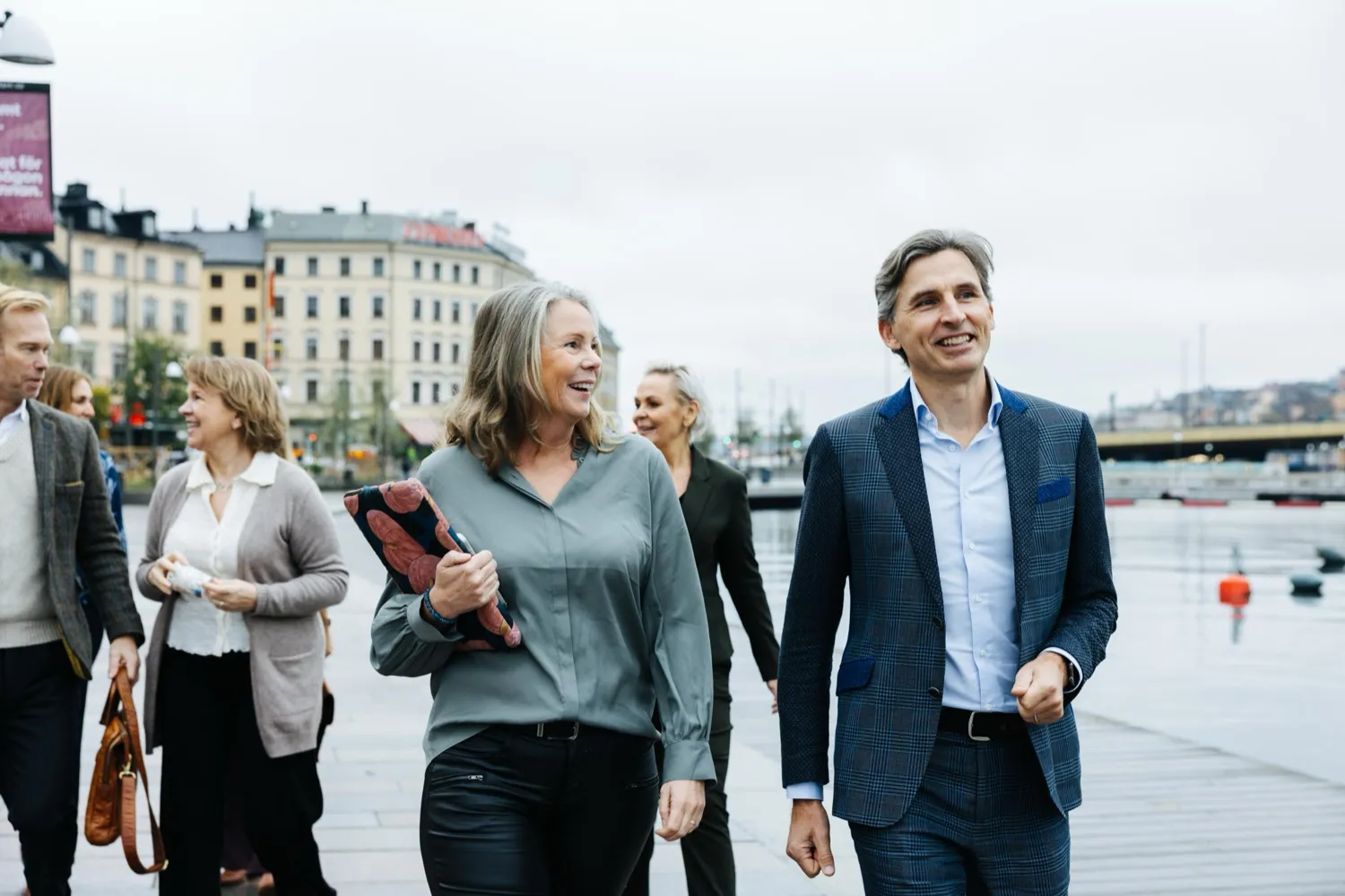 Two consultants walking along the quay in Stockholm, colleagues behind them