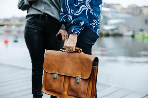 A leather briefcase in a hand on the quay